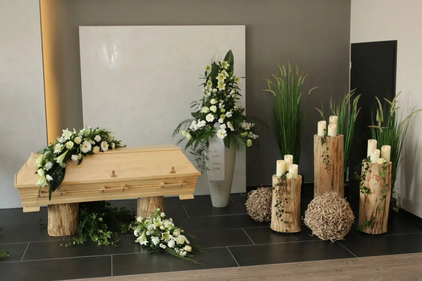 Heller Holzsarg mit weißer Floristik und Kerzen