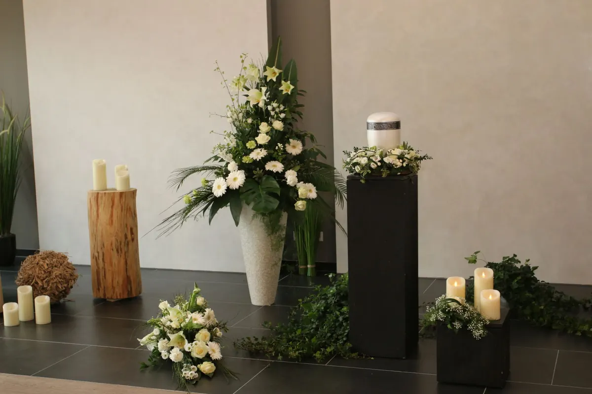 Urnenaufbahrung mit weißen Blumen und Kerzen