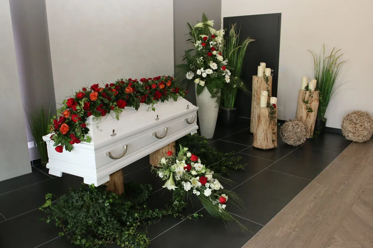 Weißer Sarg mit roten Rosen im Abschiedsraum