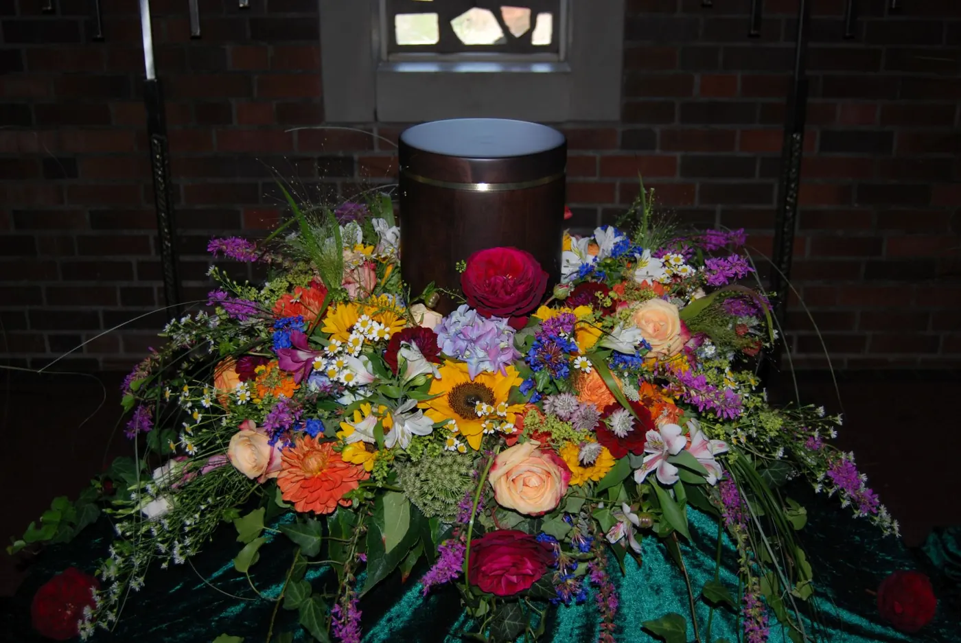 Dunkle Urne in einem bunten Blumenkranz
